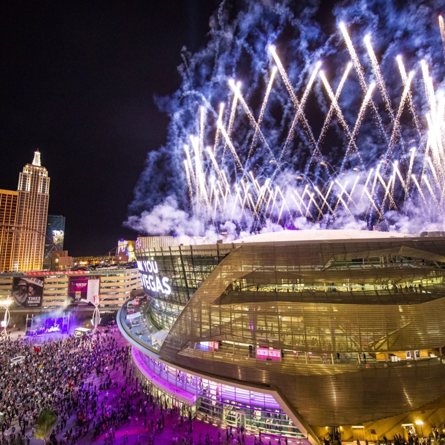 Fireworks over T-Mobile Arena at night, with crowds gathered on the plaza below